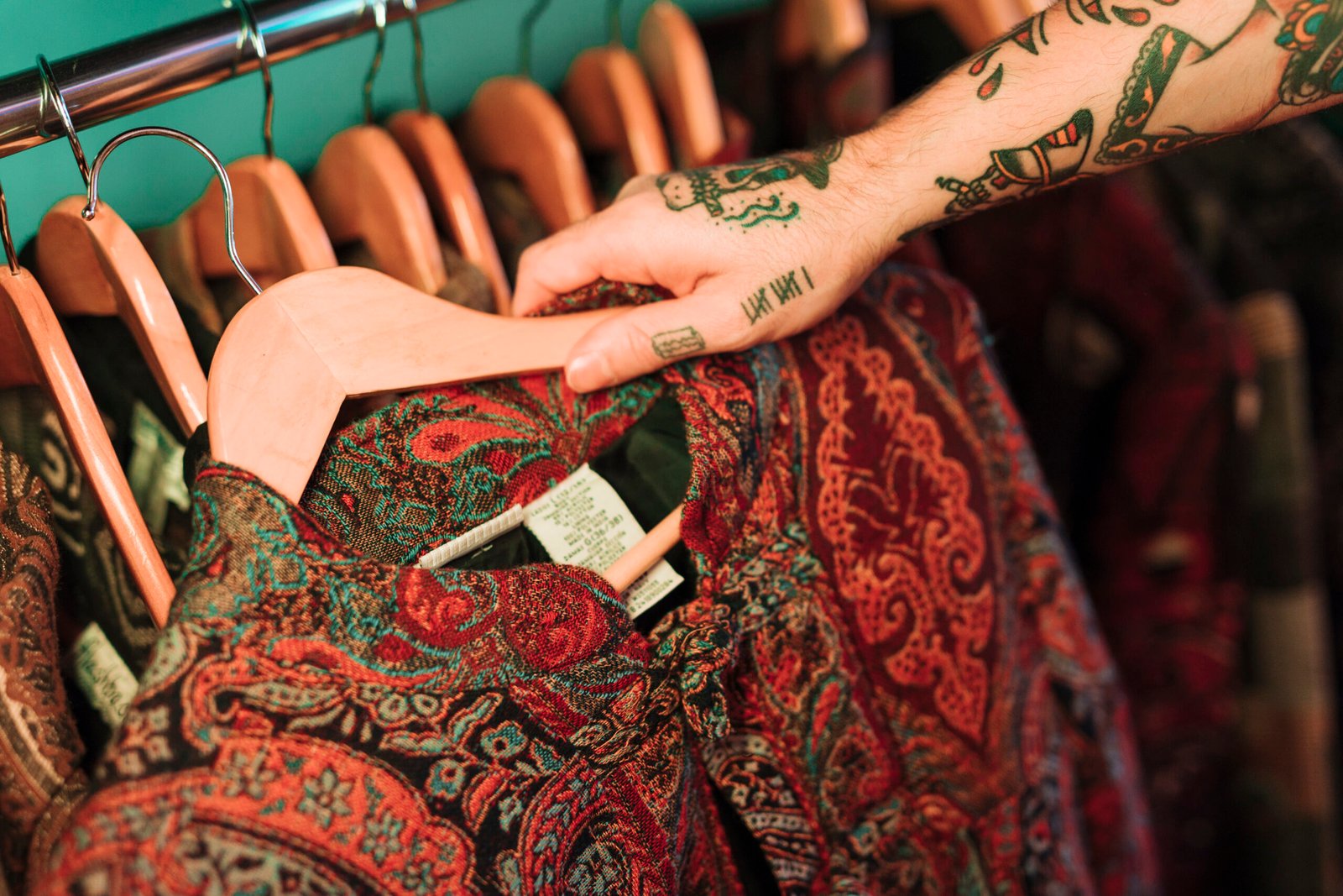 overhead view man with tattoo his hand looking clothes hanging rail